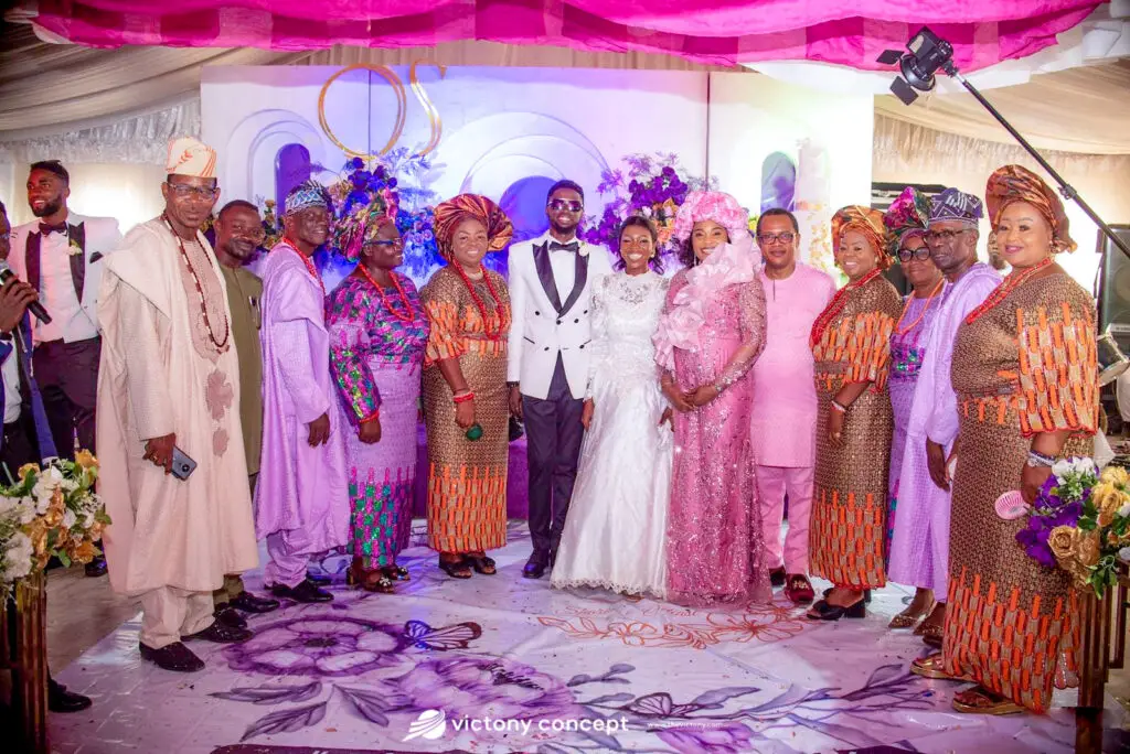 Bride, groom, and family members in colorful traditional attire posing together at a wedding reception, styled by Victony Event Planners