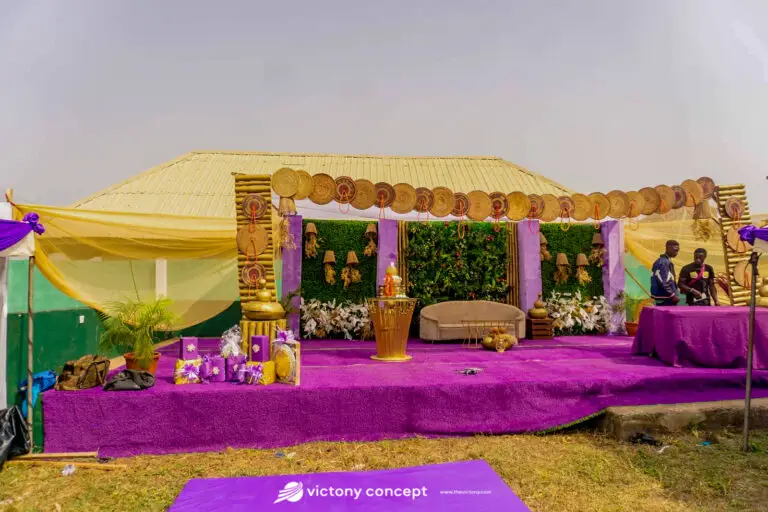 Purple and gold traditional wedding stage decor with a woven canopy and round rattan hangings, styled by Victony Event Planners