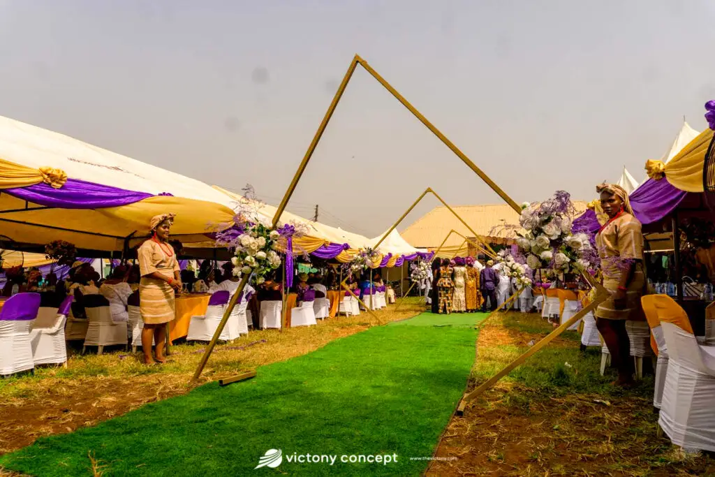 Outdoor wedding reception with purple and white floral drapery and seated guests, styled by Victony Event Planners